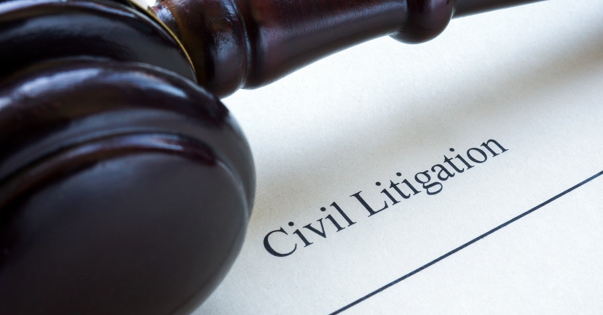 A close up of a civil litigation document placed beside a gavel on a surface with text visible on the paper.