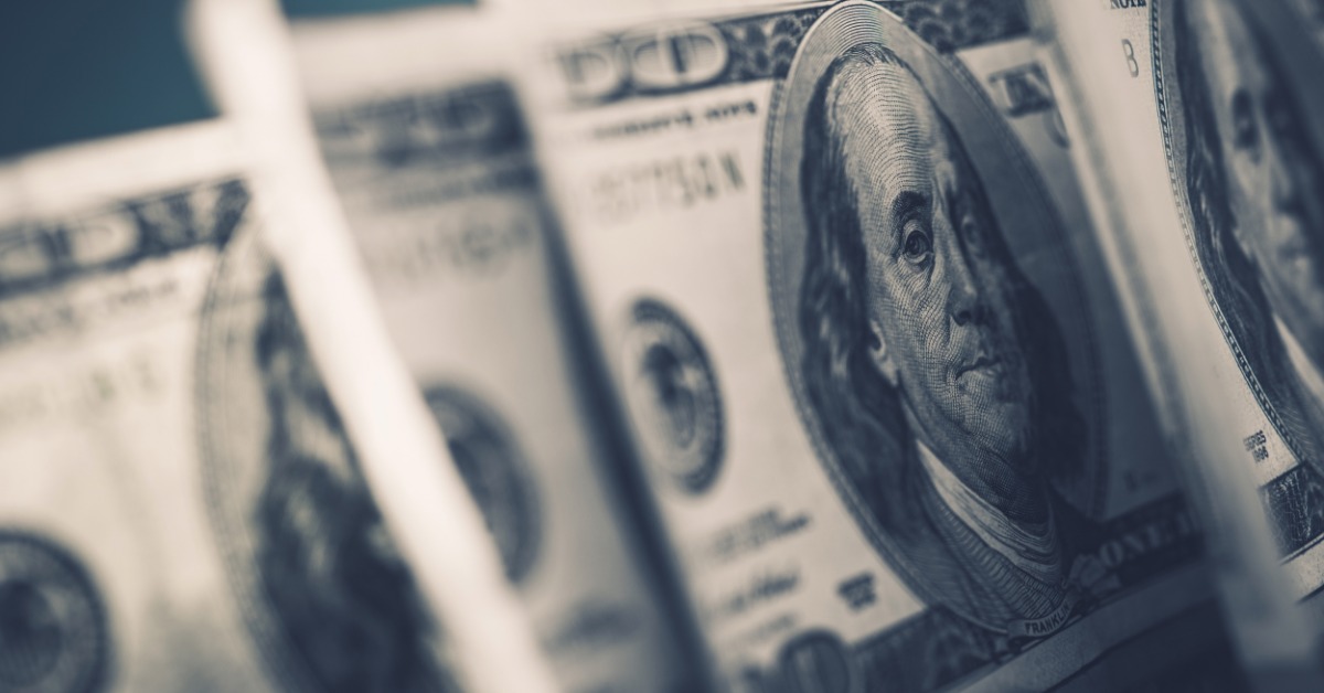 A close up of stacked American dollar bills with parts of the notes overlapping and printed details in focus.