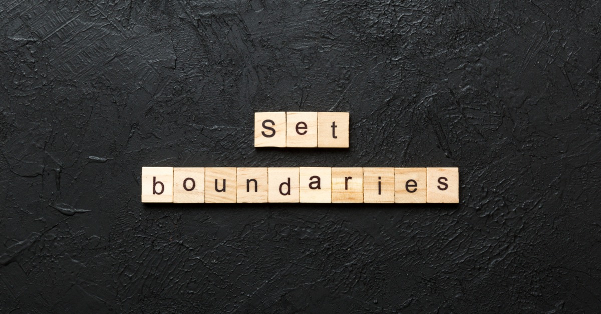 Wooden letter tiles spelling set boundaries on a dark textured surface with empty space around the words.