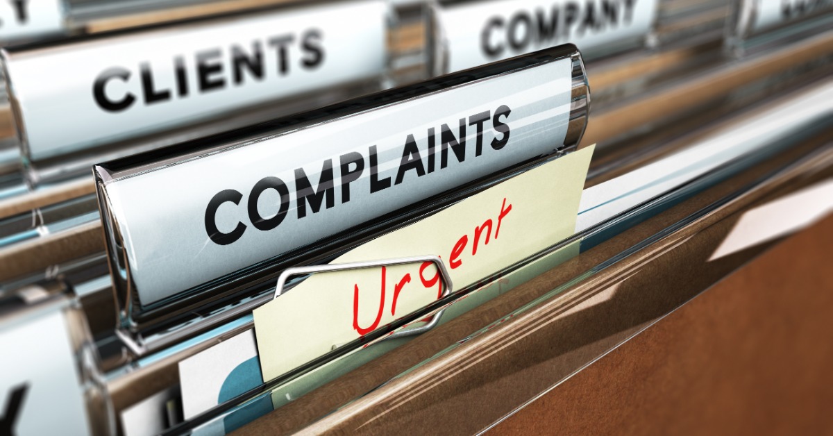 A complaint folder holding papers and an urgent note among labeled office files for clients and company records.